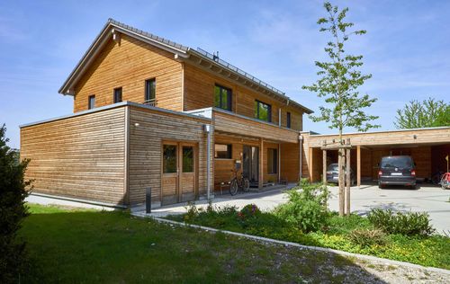 Modernes Holzhaus im Landhausstil mit Holzfassade aus Lärchenholzbohlen und Doppelcarport