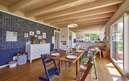 Das Esszimmer des modernen Holzhauses im Landhausstil mit Holzfassade aus Lärchenholzbohlen und Doppelcarport