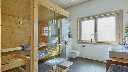 Die Sauna des schmalen, modernen Holzhauses mit mineralischem Putz und Farbakzenten