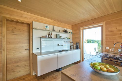 Die Küche des modernen Holzhauses mit Holzverschindelung aus Tannenholz und geschützem Balkon- und Terrassenbereich