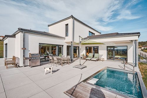 Die Terrasse des modernen Bungalows aus Holz im Bauhausstil mit mineralischem Außenputz mit Pool