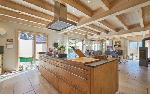 Die Küche des modernen Holzhauses im Landhausstil mit Mischfassade aus mineralischem Putz und Holz