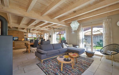 Das Wohnzimmer des modernen Holzhauses im Landhausstil mit Mischfassade aus mineralischem Putz und Holz