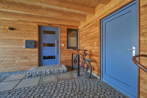 Die Eingangstür des modernen Doppelhauses aus Holz mit Mischfassade aus mineralischem Außenputz und Holz