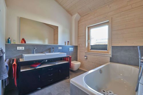 Das Badezimmer des modernen Doppelhauses aus Holz mit Mischfassade aus mineralischem Außenputz und Holz