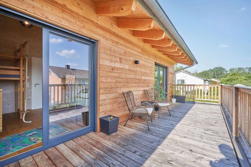 Der Balkon des modernen Doppelhauses aus Holz mit Mischfassade aus mineralischem Außenputz und Holz