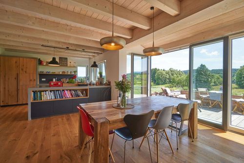 Das Esszimmer des modernen Holzhauses im Landhausstil mit durchgängiger Lärchenholzfassade und Holz-Alu-Fenstern