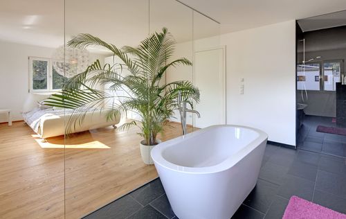 Das direkt an das Schlafzimmer angrenzende Badezimmer des Modernen Holzkubuses am Hang mit Holzfassade mit freistehender Badewanne