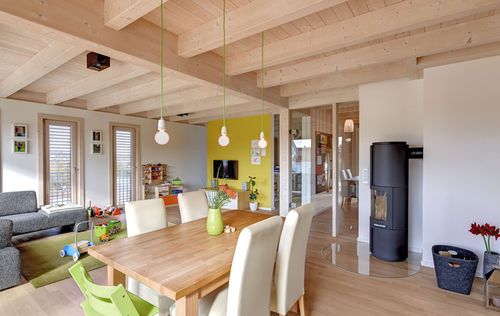 Der Wohn- und Essbereich des modernen Holzhauses mit mineralischem Außenputz und steilem Satteldach