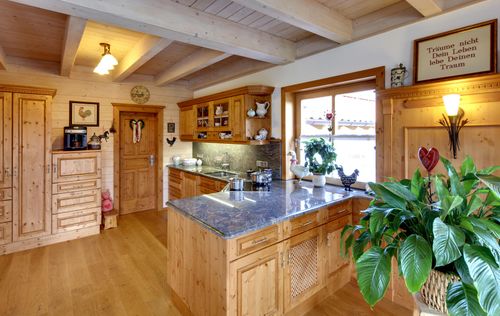 Die Küche des traditionellen Holzhauses im Landhausstil mit Mischfassade aus Holz und Putz
