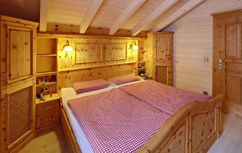 Das Schlafzimmer des traditionellen Holzhauses im Landhausstil mit Mischfassade aus Holz und Putz