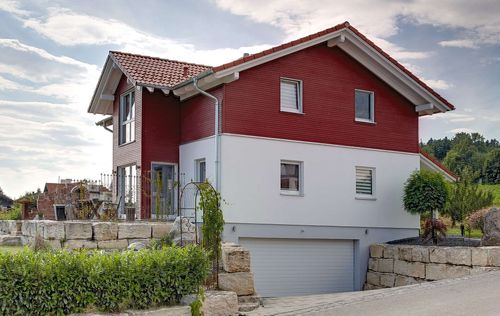 Seitliche Ansicht des Holzhauses im Landhausstil mit gemischter Fassade aus mineralischem Putz und Holz