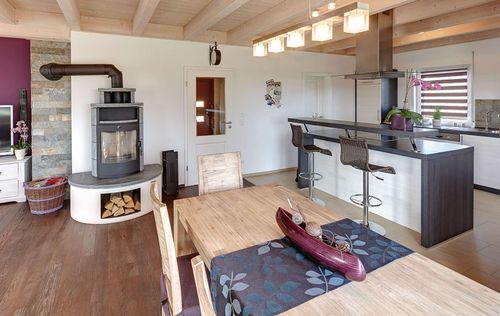 Die Küche und der Essbereich des Holzhauses im Landhausstil mit gemischter Fassade aus mineralischem Putz und Holz