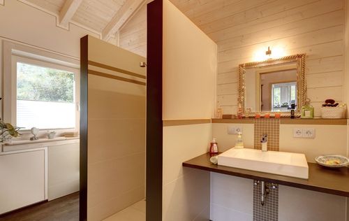 Das Badezimmer des Bungalows aus Holz auf Hanggrundstück mit ausgebautem Keller mit viel Glas