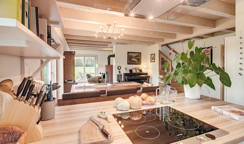Die Küche des modernen Holzhauses mit Pultdach und gemischter Fassade aus mineralischem Putz und Lärchenholz