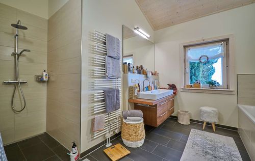 Das Badezimmer des Bungalows aus Holz mit umlaufender, teilweise überdachter Terrasse