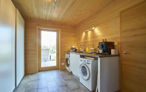 Die Waschküche des modernen Holzhauses mit Holzverschindelung aus Tannenholz und geschützem Balkon- und Terrassenbereich
