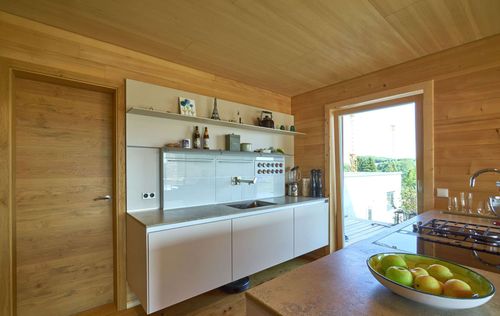 Die Küche des modernen Holzhauses mit Holzverschindelung aus Tannenholz und geschützem Balkon- und Terrassenbereich