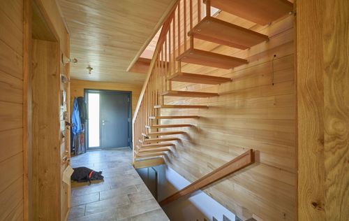 Die Treppen des modernen Holzhauses mit Holzverschindelung aus Tannenholz und geschützem Balkon- und Terrassenbereich