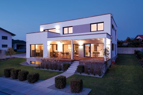 Modernes Holzhaus im Bauhausstil mit mineralischem Außenputz und Flachdach bei Nacht