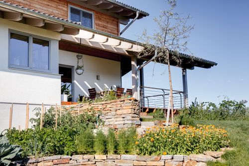 Die Terrasse des modernen Holzhauses im Landhausstil auf einem Hanggrundstück