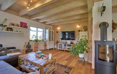 Das Wohnzimmer des traditionellen Holzhauses mit Mischfassade aus Lärchenholz und Putz, mit flachem Satteldach und hohem Kniestock