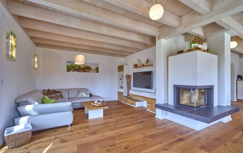 Das Wohnzimmer des modernen Holzhauses im Stadtvilla-Stil mit mineralischem Außenputz und teilweise überdachter Terrasse