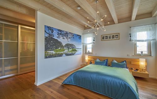 Das Schlafzimmer des modernen Holzhauses im Stadtvilla-Stil mit mineralischem Außenputz und teilweise überdachter Terrasse