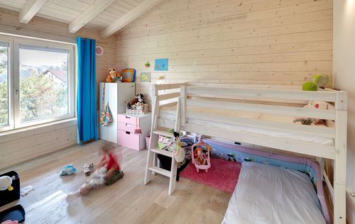 Das Kinderzimmer des modernen Holzhauses im Landhausstil mit durchgängiger Holzfassade