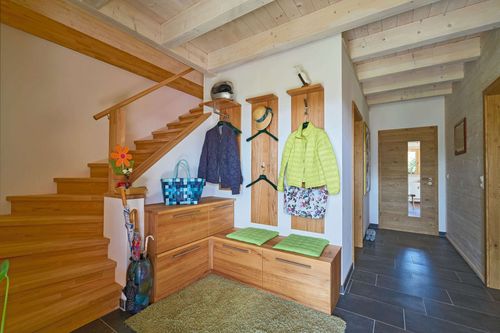 Die Diele des modernen Holzhauses im Landhausstil mit flachem Satteldach und gemischter Fassade aus Lärchenholz und mineralischem Außenputz