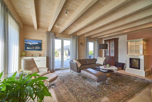Das Wohnzimmer des modernen Holzhauses mit Mischfassade aus Holz und Putz und komfortabler Ausstattung