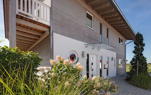 Modernes Holzhaus mit umlaufendem Balkon und Mischfassade aus Holz und Putz