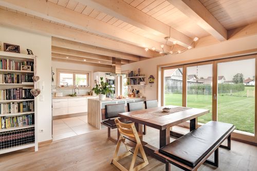 Die Küche und der Essbereich des modernen Holzhauses mit Pultdach und gemischter Fassade aus mineralischem Putz und Lärchenholz