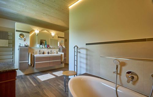 Das Badezimmer des modernen Holzhauses im Bauhausstil mit drei Gebäudetrakten, zwei davon mit mineralischem Außenputz und Flachdach, einer mit Holzfassade aus Fichtenholzbohlen und Pultdach