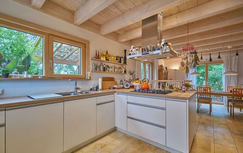 Die Küche des modernen Holzhauses im Landhausstil mit durchgängiger Lärchenholzfassade und großer Terrasse