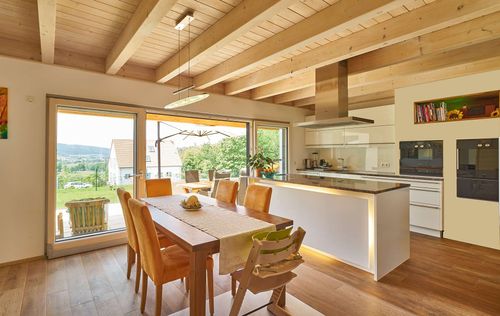 Die Küche des modernen Holzhauses im Landhausstil mit Mischfassade aus Fichtenholz und mineralischem Außenputz