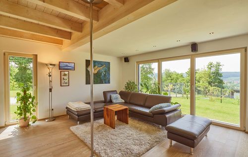 Das Wohnzimmer des modernen Holzhauses im Landhausstil mit Mischfassade aus Fichtenholz und mineralischem Außenputz