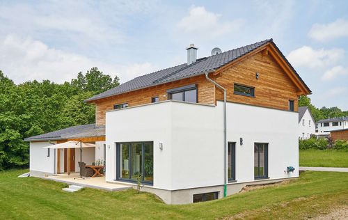 Modernes Holzhaus im Landhausstil mit Mischfassade aus Fichtenholz und mineralischem Außenputz