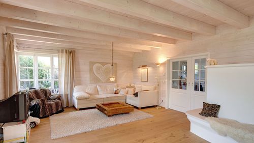Das Wohnzimmer des traditionellen Holzhauses mit durchgängiger, grauer Holzfassade, inspiriert von unserem Musterhaus 'St. Johann'